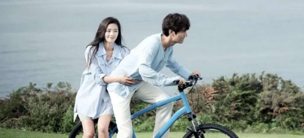 Couple riding bicycle near ocean