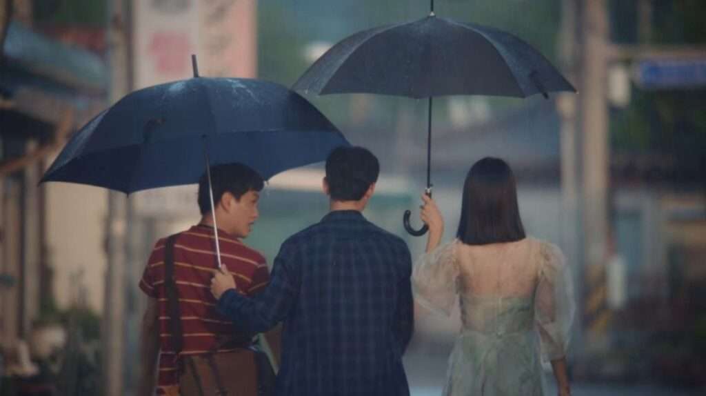 Three friends walking with umbrellas