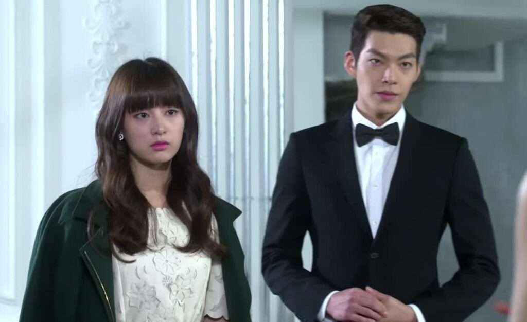 Formal couple standing, looking concerned. 