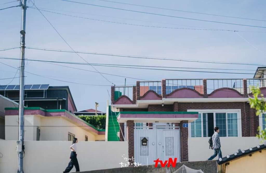 People walking by rooftop house.