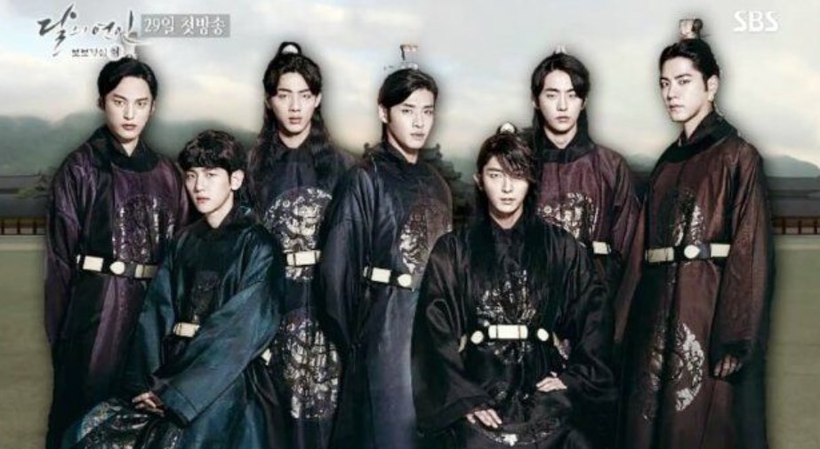 Group of seven men dressed in traditional Korean hanbok attire, standing together in a historical setting. They are part of a royal-themed drama, showcasing a regal and majestic atmosphere with their striking outfits and confident poses.