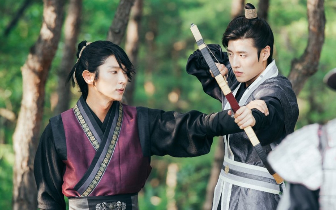 Moon Lovers: Scarlet Heart Ryeo intense training scene between Lee Joon-Gi and Kang Ha-Neul, showcasing their competitive rivalry and camaraderie in traditional martial arts attire, set in a serene forest backdrop.