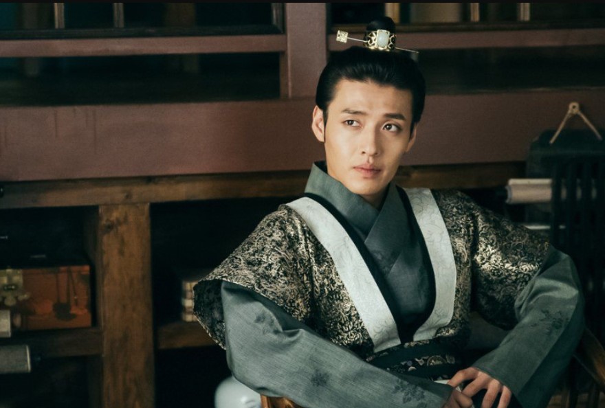 Moon Lovers: Scarlet Heart Ryeo close-up of Kang Ha-Neul in royal attire, sitting thoughtfully with a calm yet intense expression, capturing his character's depth and inner conflict in a traditional setting