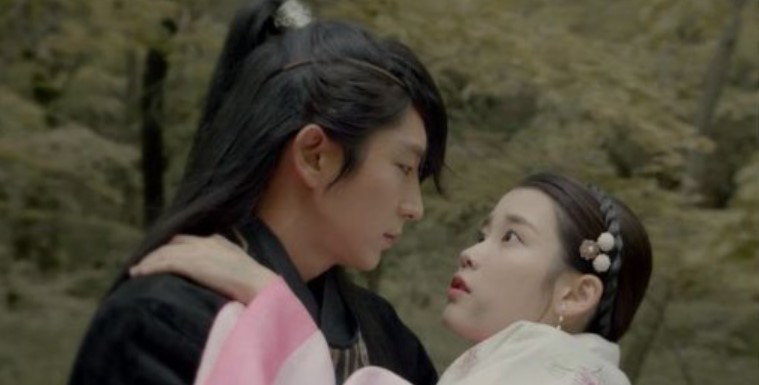 Moon Lovers: Scarlet Heart Ryeo romantic moment between IU and Lee Joon-Gi, with Lee Joon-Gi holding IU in his arms as they share an intense gaze, set in a serene natural background, highlighting their deep emotional connection.