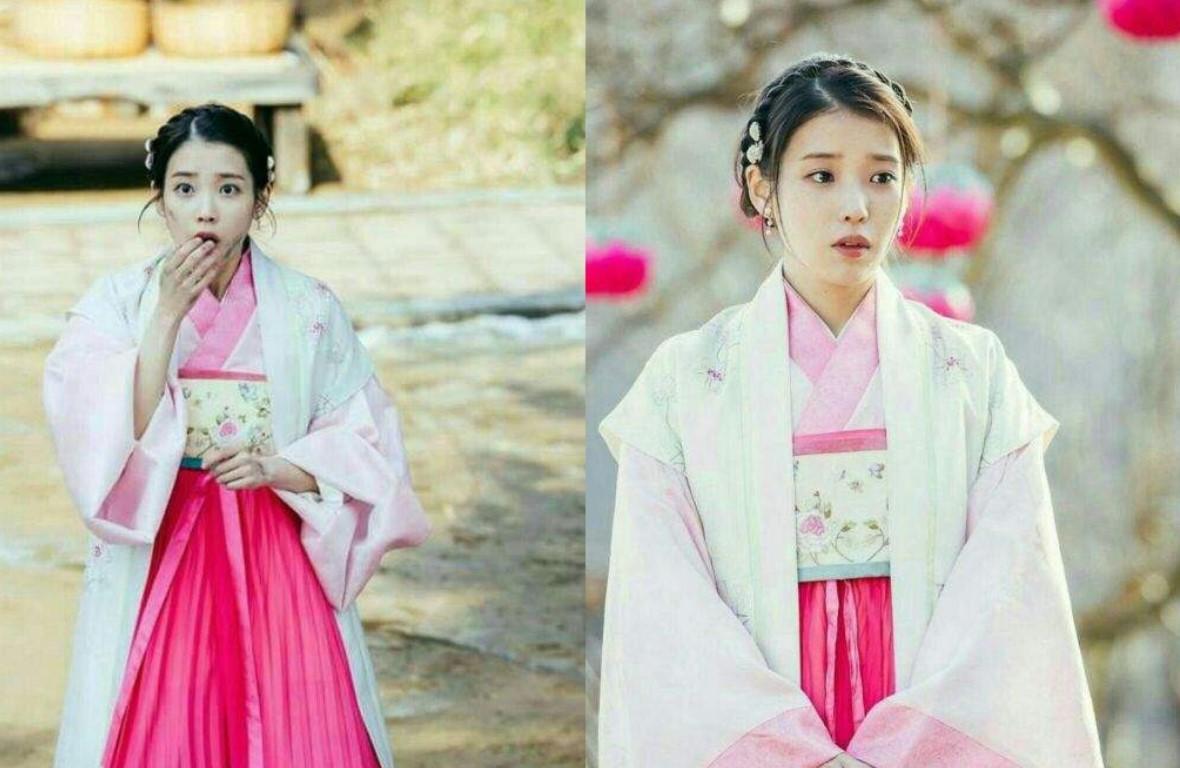 Moon Lovers: Scarlet Heart Ryeo candid moment of IU in a pink hanbok, expressing surprise and curiosity with a hand over her mouth, capturing the playful and innocent side of her character in a vibrant outdoor setting.