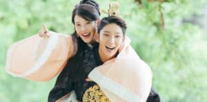 Moon Lovers: Scarlet Heart Ryeo joyful and playful moment between IU and Lee Joon-Gi, as IU rides piggyback on Lee Joon-Gi, both smiling brightly in traditional royal attire, showcasing the carefree and affectionate side of their relationship.