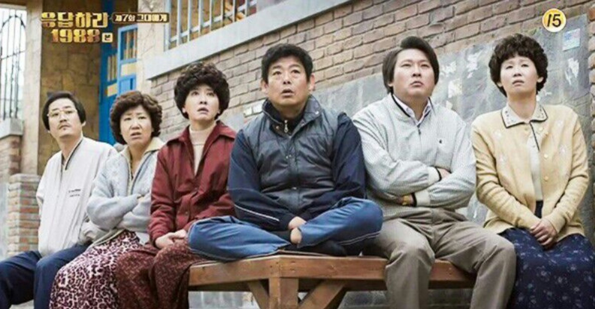 Parents from Reply 1988 sitting together, sharing a moment of contemplation in the iconic 1980s neighborhood setting.