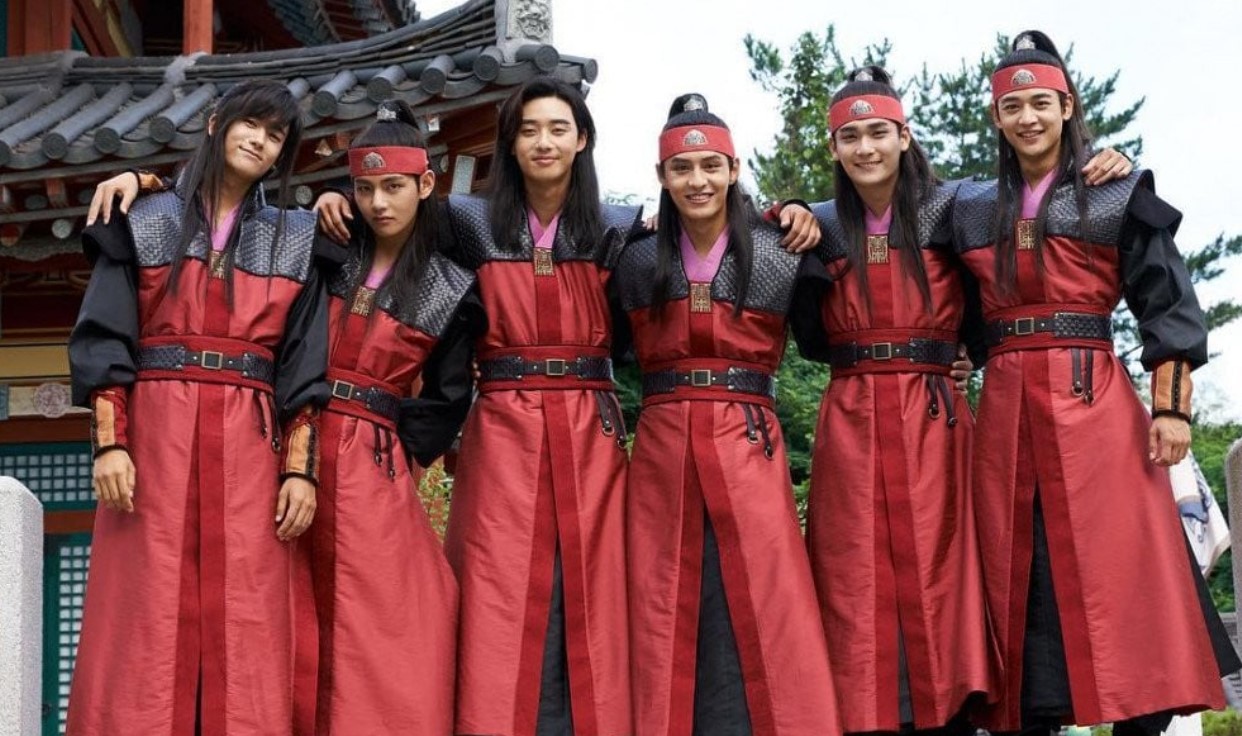 The main group of Hwarang warriors posing together in their striking red and black uniforms. With smiles and relaxed postures, the group showcases camaraderie and strength, ready for action. Their traditional attire, complete with headbands, adds to the warrior spirit of the series.
