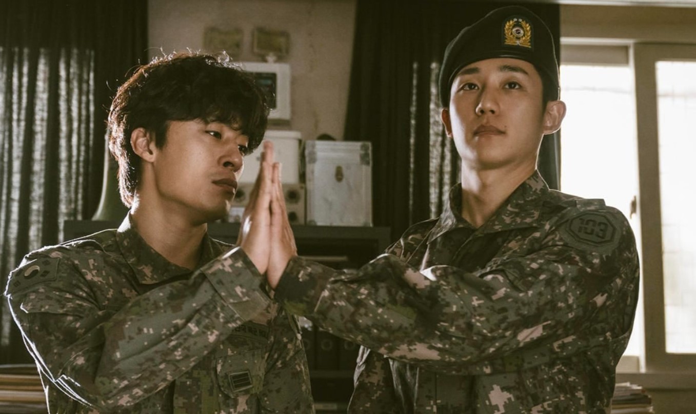 DP Season 1 scene showing two soldiers in military uniform performing a hand gesture, symbolizing trust and camaraderie amidst the intense and emotional moments of the drama. This powerful image captures the deep bond between the characters.