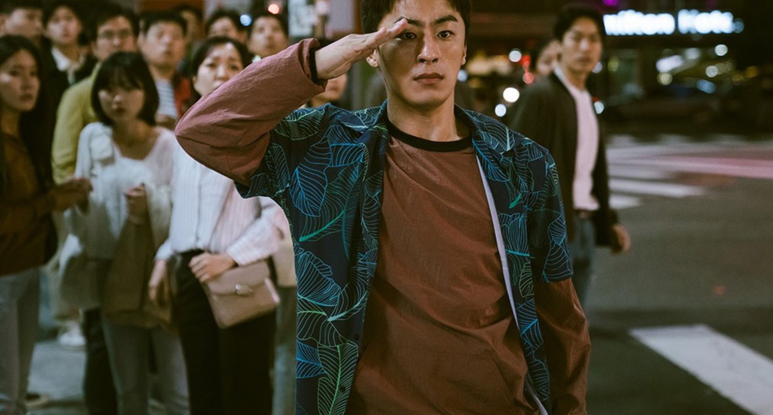 A soldier in casual clothing saluting in a crowded city street. People in the background watch in surprise, with city lights and a sense of drama surrounding the moment