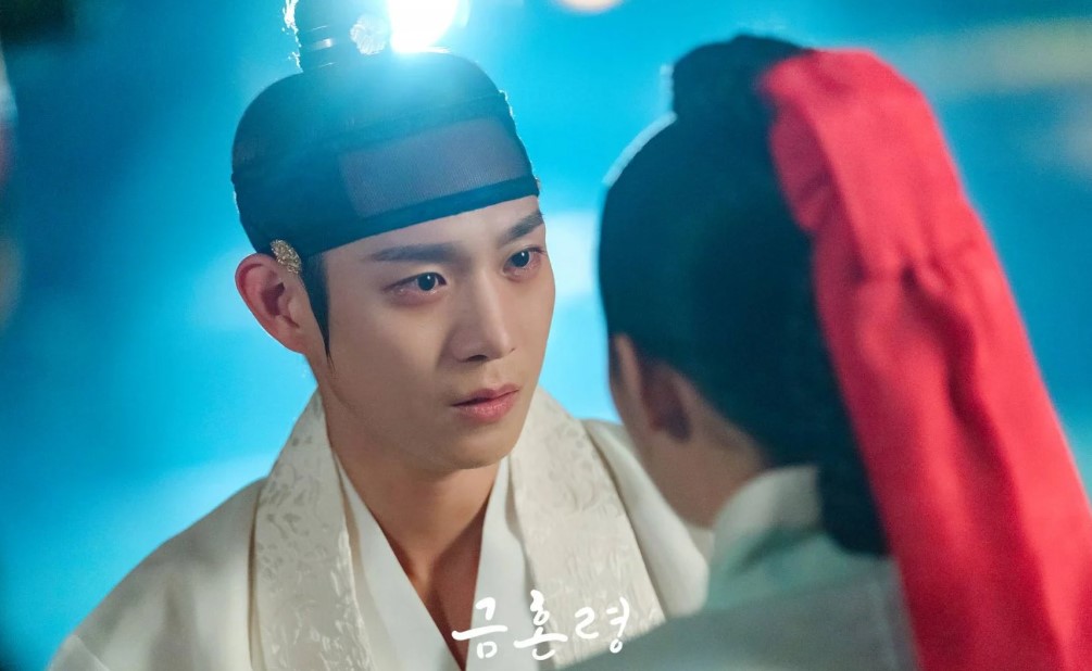 Close-up of the male lead from The Forbidden Marriage, gazing intensely at the female lead, with a dramatic and emotional moment illuminated by soft lighting, set in a traditional Korean backdrop.