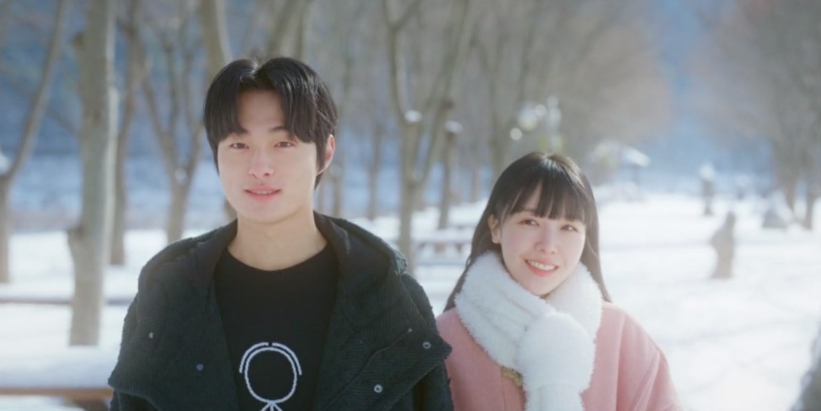 A warm and cheerful scene from The Delivery Man, showing the two main characters walking together in a snowy park. The man smiles gently while the woman, wrapped in a cozy scarf, beams happily, creating a heartwarming moment between them.