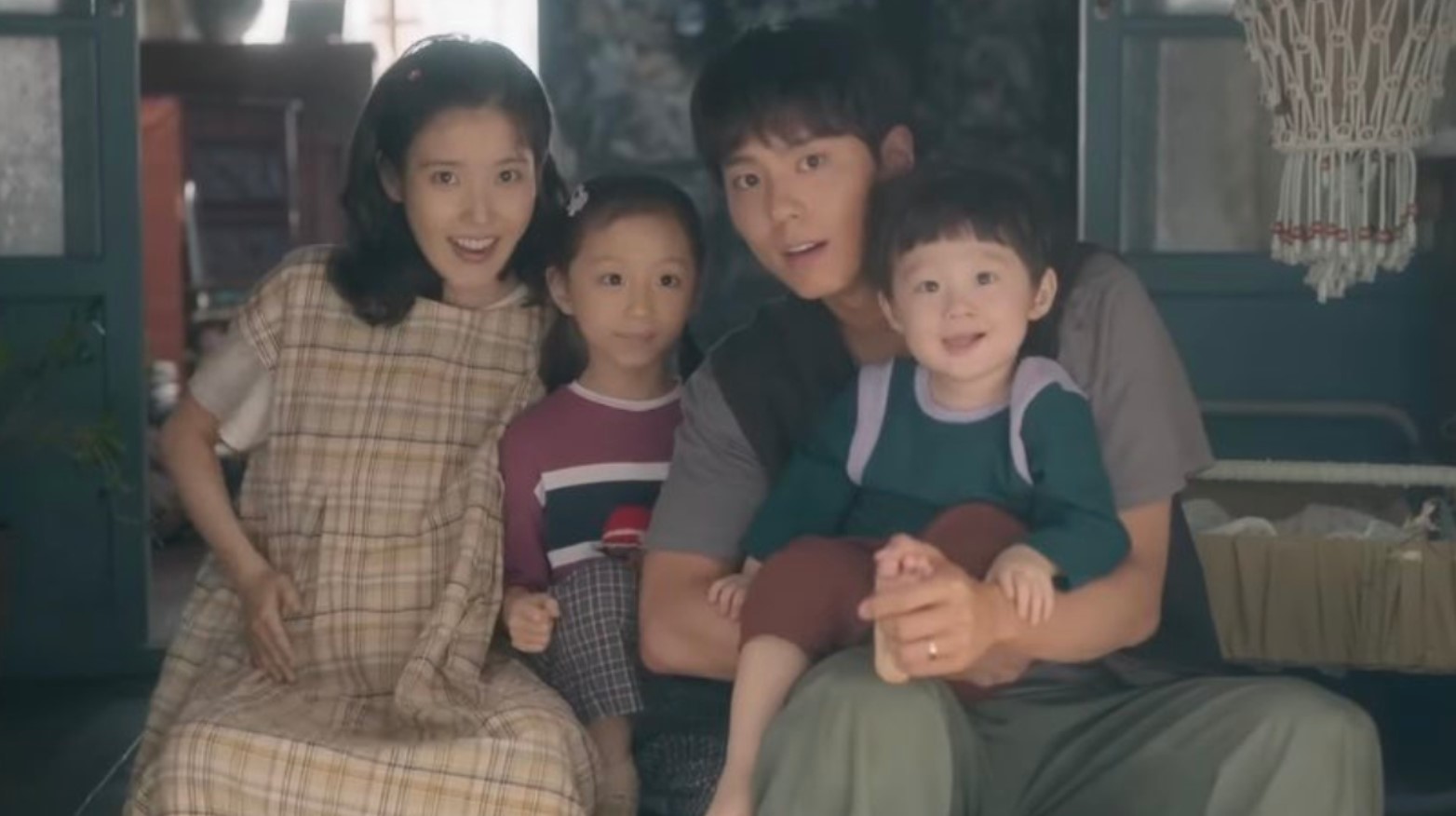 A happy family posing together in a cozy indoor setting, featuring a pregnant woman, a man with two young children, in the scene from the K-drama When life gives you tangerine. Featured in Best K-Drama Reviews 2025