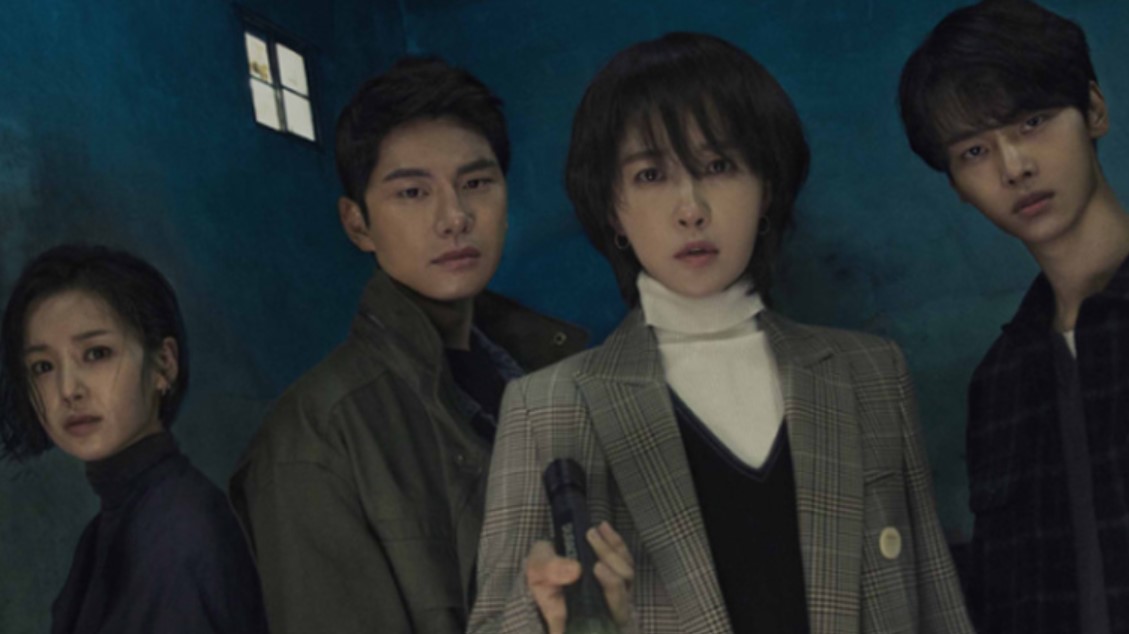 Intense scene from the Korean drama Children of Nobody, featuring the main characters standing in a dimly lit room, conveying a tense atmosphere. The woman at the forefront holds a bottle, while the others stand behind her, reflecting the suspense and mystery of the series. Children of Nobody is a gripping psychological drama with elements of crime and thriller.