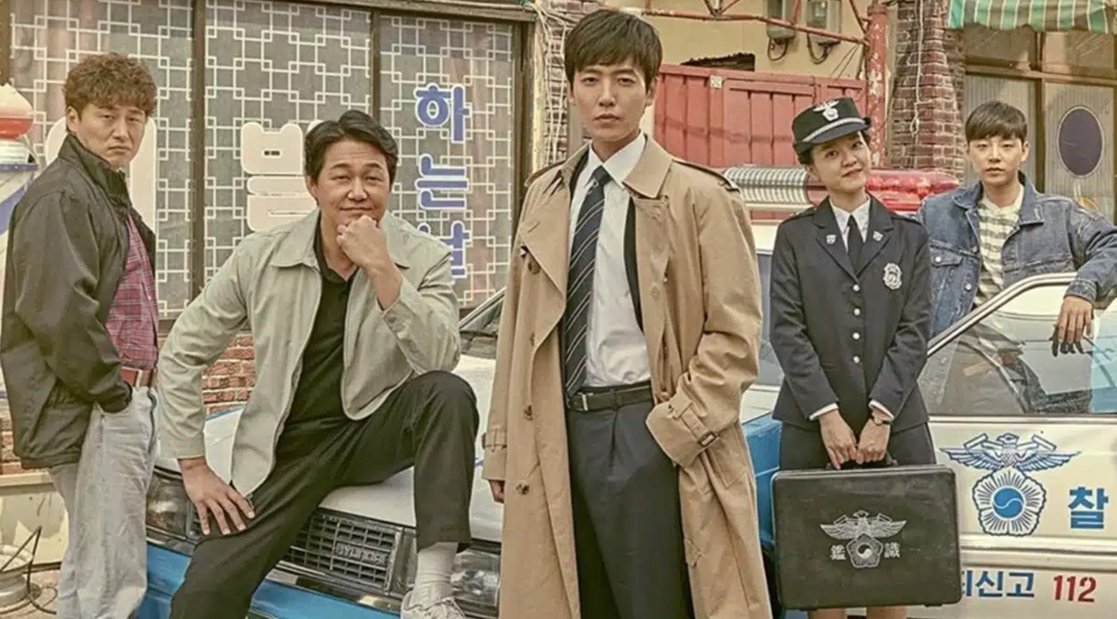 Group photo from the Korean drama Life on Mars (2018), featuring the main characters standing in front of a police car. The cast includes a mix of detectives and officers with distinct personalities, ready to solve mysteries in a crime-ridden world. The image captures the dynamic teamwork and camaraderie in this thrilling, time-traveling detective drama.