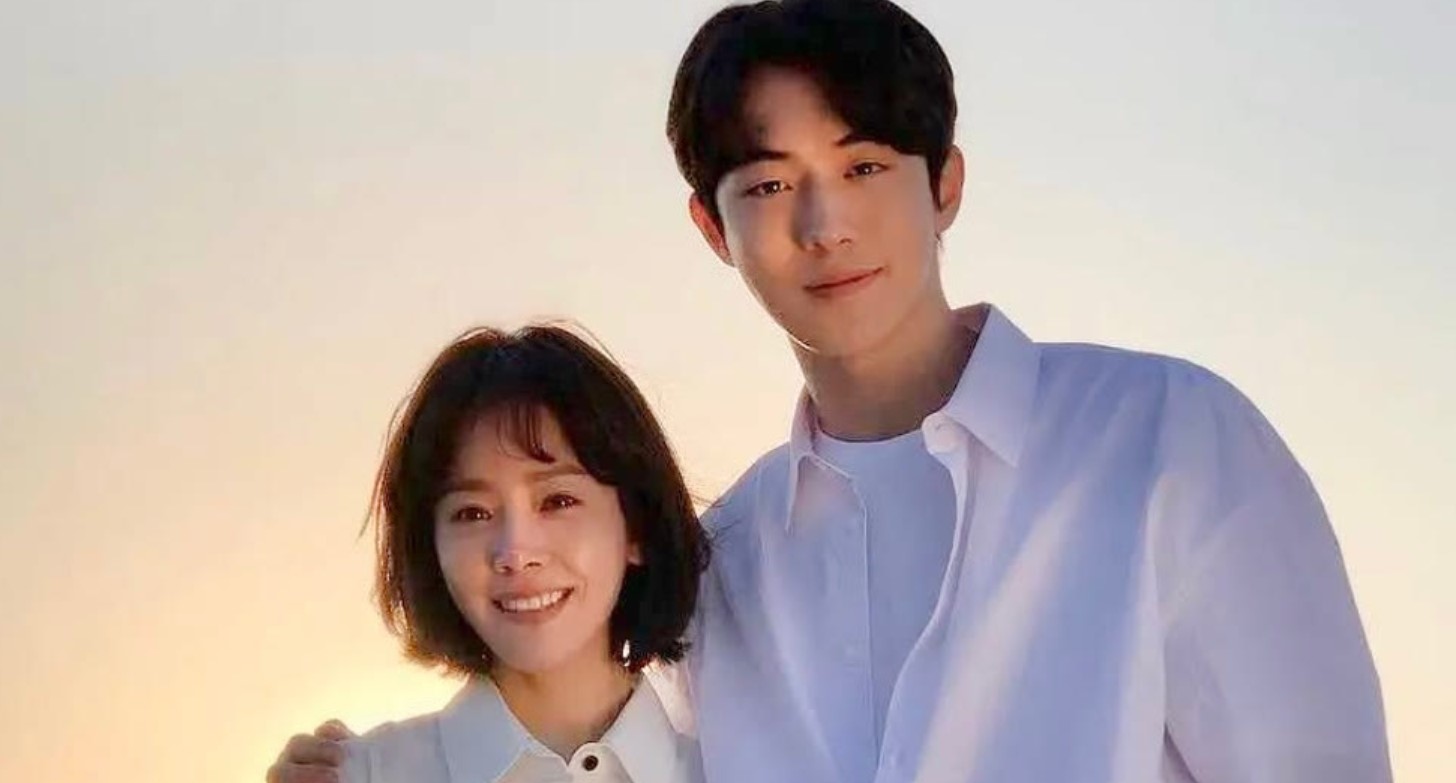 Charming scene from the Korean drama The Light in Your Eyes (2019), also known as Radiant, featuring the lead couple standing together in the warm glow of the sunset. Both characters share a heartfelt moment, with the woman smiling at the man, who beams back. This touching series explores the themes of time, love, and the power of second chances.