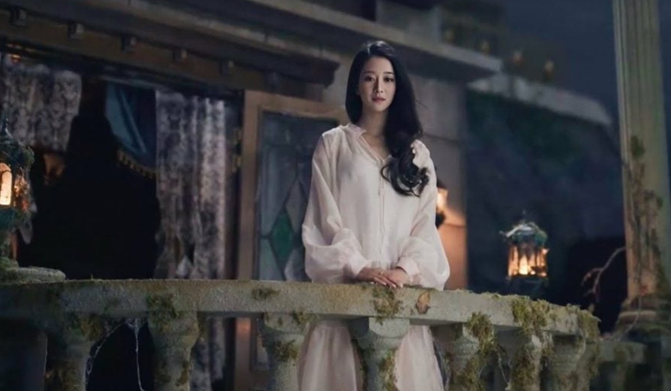 Drama character development in 'It's Okay to Not Be Okay' as the female lead stands on a balcony in a reflective moment, capturing her emotional growth and journey in the gothic setting of the scene.