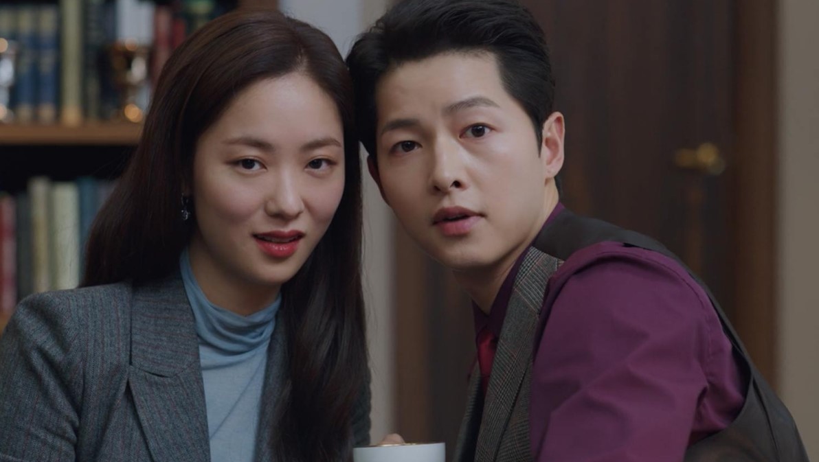 Vincenzo Cassano and Hong Cha-young sharing an intimate moment in the drama Vincenzo, with both characters looking intrigued while sitting together in a cozy, stylish setting.