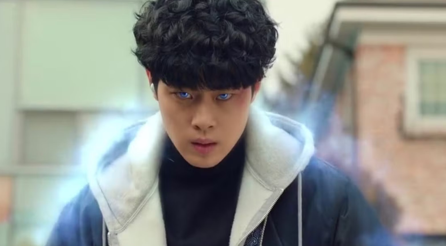 A man with blue eyes and a hoodie, depicted in a moment from a supernatural drama.