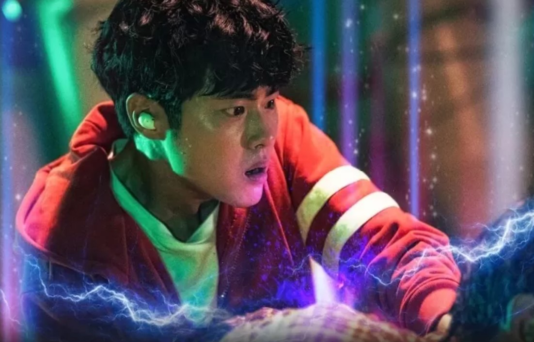 Main character from Uncanny Counter Season 1 – a young man in a red hoodie, focused and determined, with electric energy surrounding him. Uncanny Counter Season 1 full review