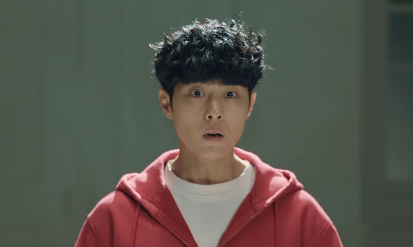 Main character from Uncanny Counter Season 1 – a young man in a red hoodie, looking shocked and surprised