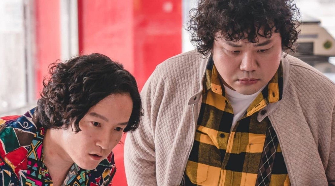 Zombie Detective K-Drama scene featuring two supporting characters inspecting something closely in a colorful setting.