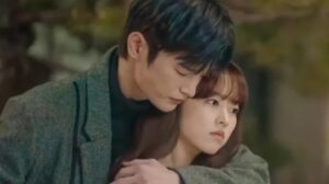 Romantic moment from Doom at Your Service with the male lead embracing the female lead in a tender outdoor setting
