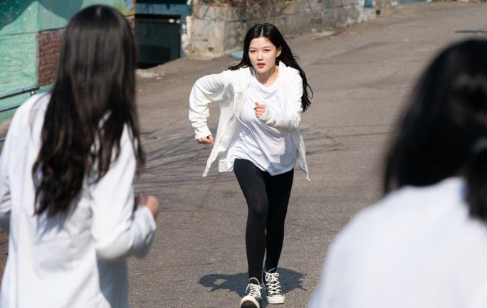 "Kim You-Jung as Jung Saet-Byul from 'Backstreet Rookie,' running in a dramatic outdoor chase scene. Dressed in a white hoodie and black leggings, her character shows determination and energy in this action-packed moment from the K-drama.