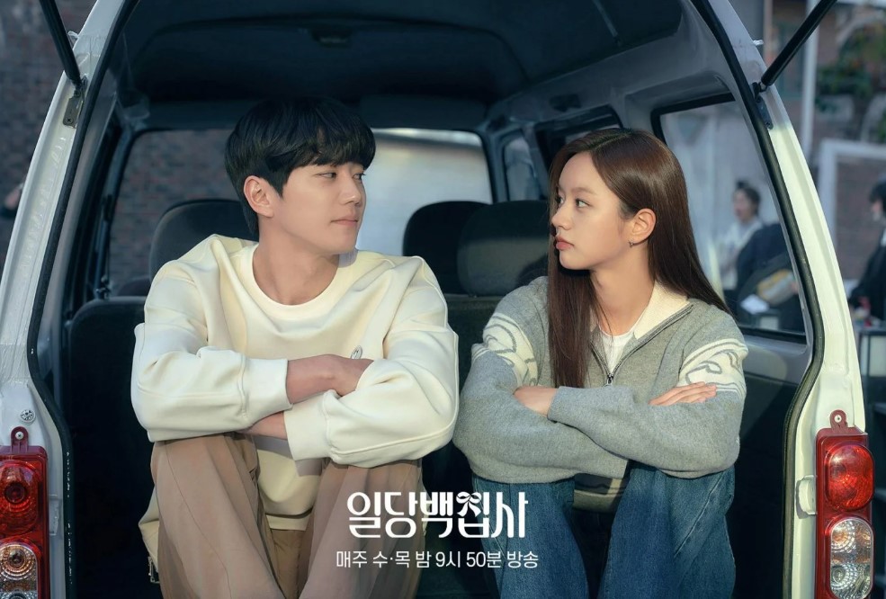 Young couple sitting in the back of a van, gazing at each other, in a romantic scene from a Korean drama.