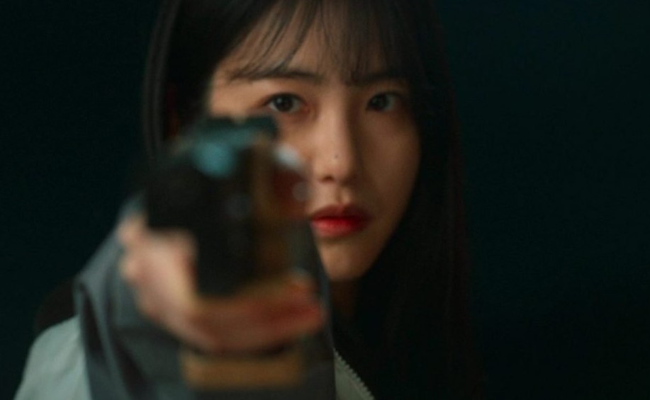 Close-up shot of a female character from 'Revenge of Others' holding a gun in a tense scene, with a focused expression, set against a dark background.