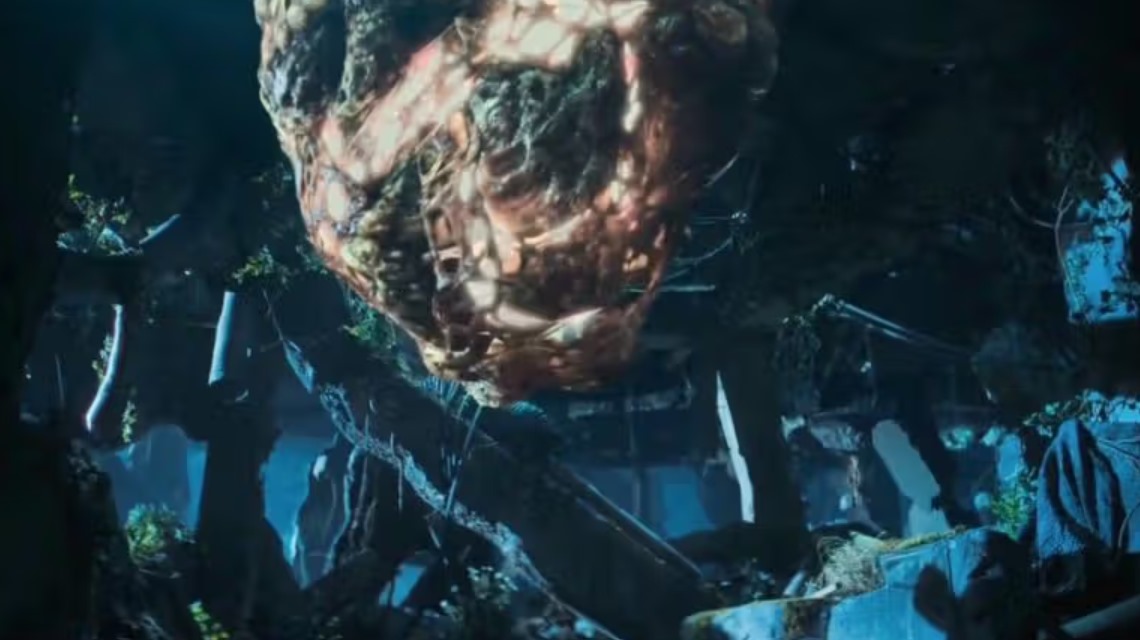 Large, glowing organic mass suspended in a dark, ruined environment, surrounded by overgrown vegetation and broken structures, creating an eerie and mysterious atmosphere.