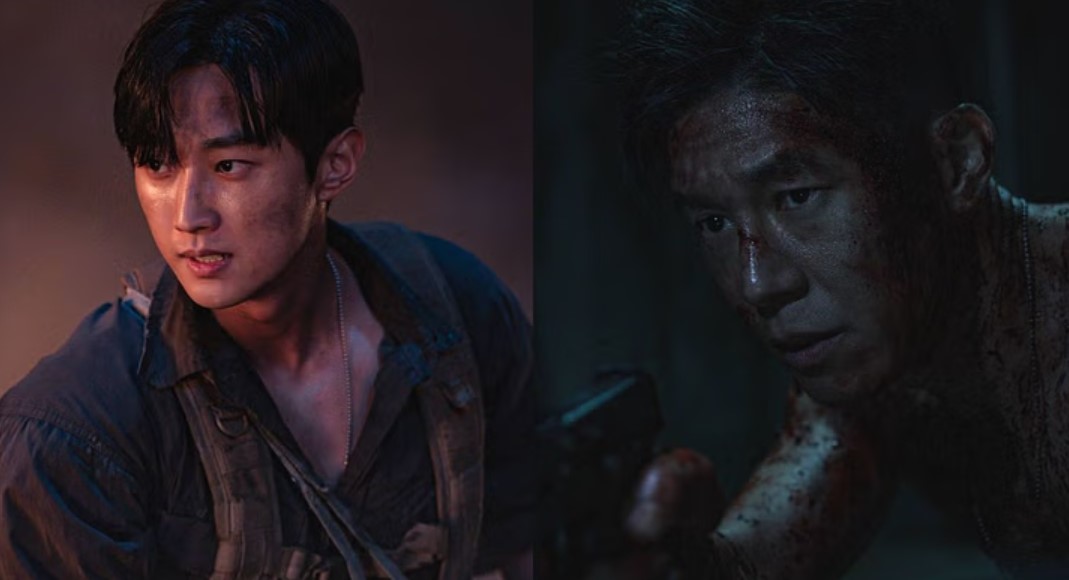Two intense male characters, one with a determined expression and visible dirt and scratches on his face, and the other covered in blood, holding a gun in a dark, gritty setting, conveying a tense and dramatic atmosphere.