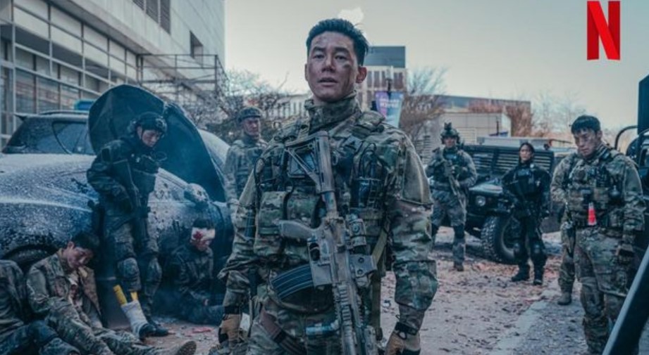 Soldier in tactical gear standing confidently amidst a chaotic scene, with fellow soldiers and injured comrades in the background, set in a post-apocalyptic urban environment.