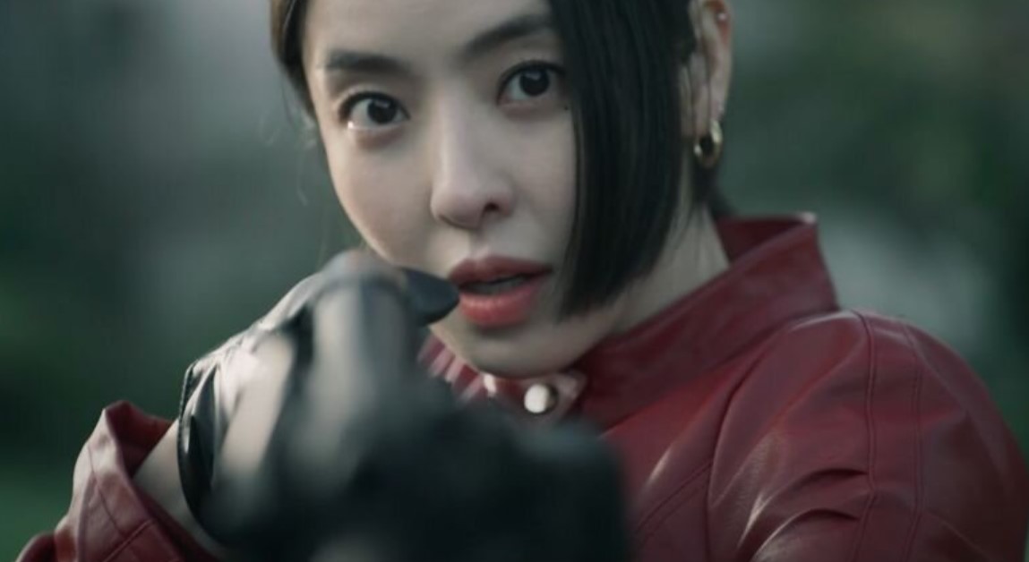 Character from 'Island' drama series aiming a gun with intense focus, wearing a red leather jacket and black gloves, capturing a dramatic and action-packed moment.