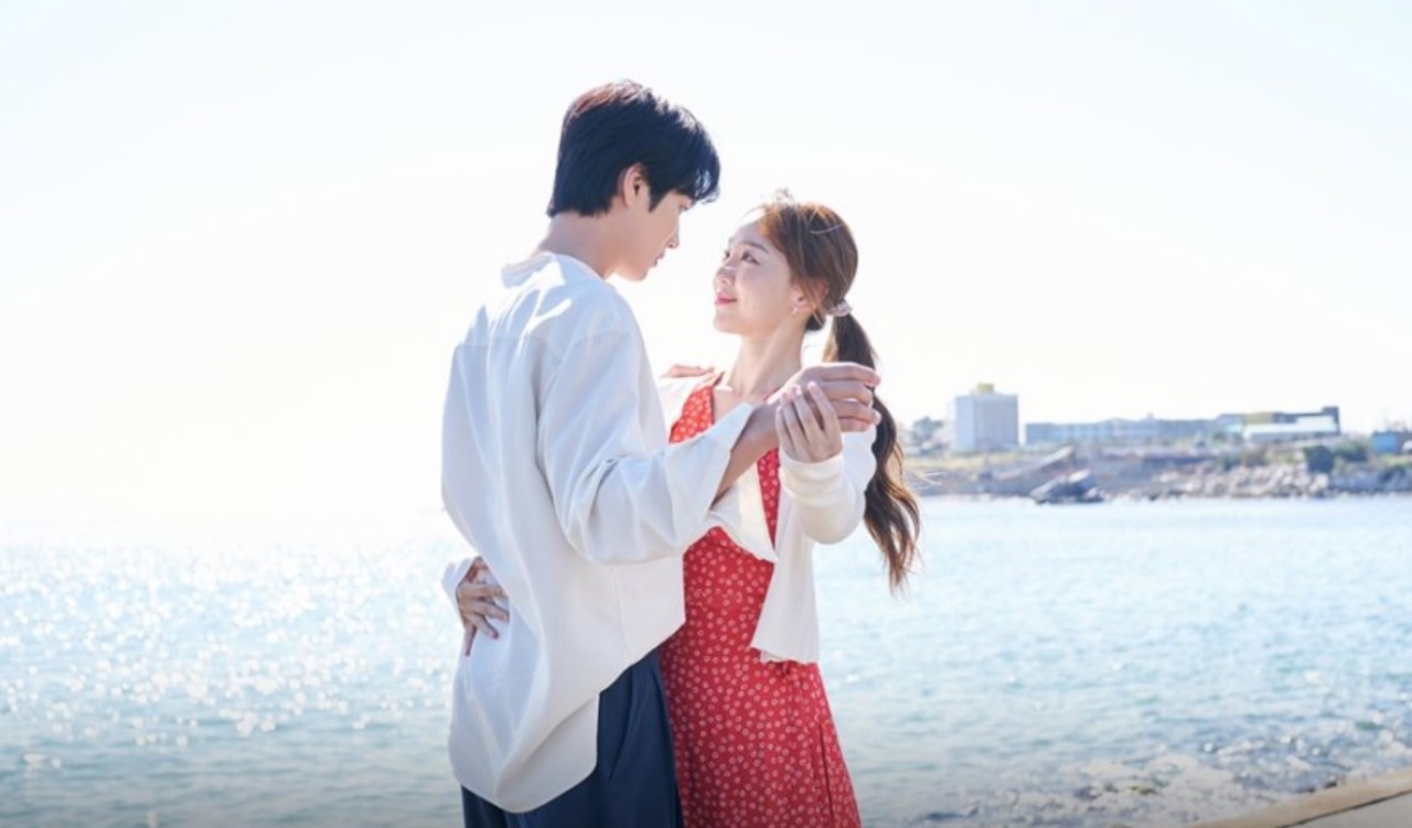 Romantic scene from 'This Life, Too, is Good,' featuring the lead couple dancing by the ocean under a clear sky, capturing a tender moment of love and connection.