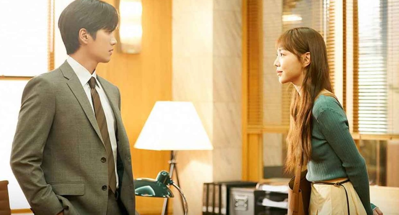 Intense scene from the K-drama 'This Life, Too, is Good,' showing a tense moment between the two lead characters, with the man in a suit and the woman in a green sweater, facing each other in an office setting.