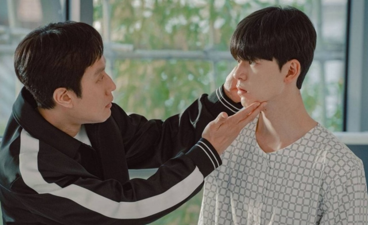 Scene from 'Miraculous Brothers' showing one character gently holding the other's chin, highlighting their emotional connection.