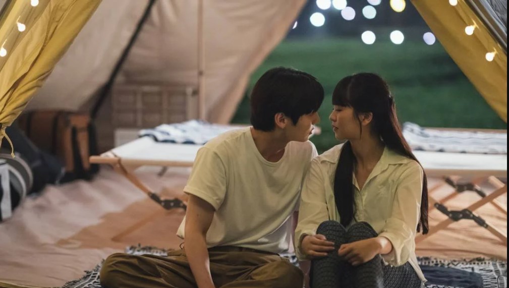 Romantic scene from 'My Lovely Liar' showing the two main characters in a tent, gazing at each other intimately. The cozy setting and soft lighting enhance the emotional tension between them.