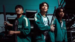Characters from Squid Game Season 1, including players wearing green tracksuits with numbers 21, 218, and 07, show intense expressions as they navigate a tense moment. The image highlights their vulnerability and suspense in the high-stakes game, making it perfect for a Squid Game season 1 full review.