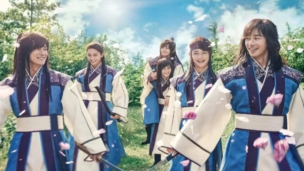 Hwarang full review: The main cast of the K-drama Hwarang, dressed in traditional hanbok, smiling and walking together in a picturesque setting with cherry blossoms. The group of young warriors showcases their camaraderie and charm, highlighting the essence of the show in this beautiful scene.