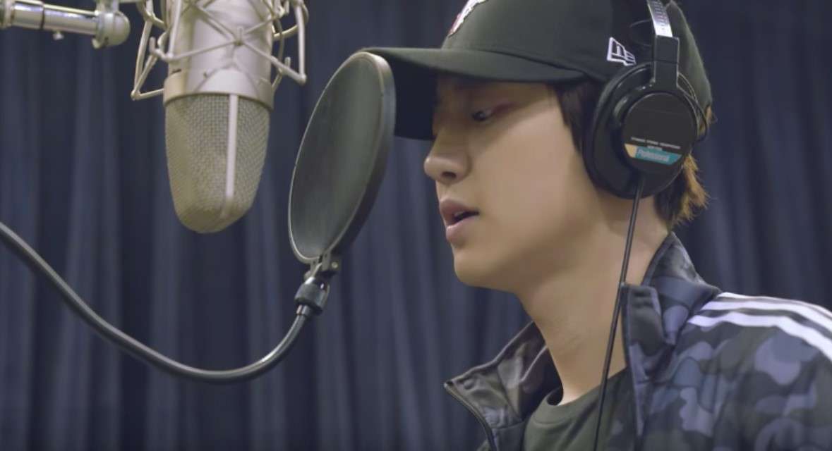 Chanyeol, a KPop idol, sings passionately into a microphone while wearing a baseball cap, showcasing his musical talent.