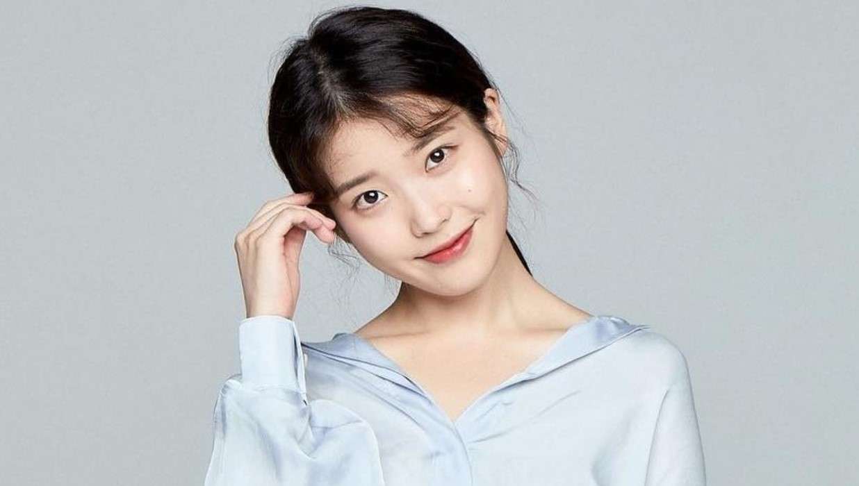 IU, a KPop idol, poses in a blue shirt for a photo, highlighting her role in KPop Idols’ Favorite OSTs.