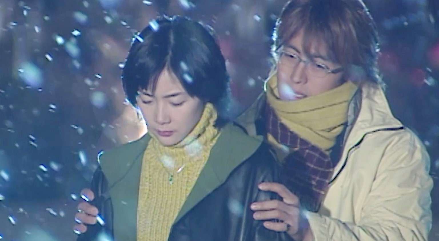  A couple in winter attire standing in the snow, reflecting the timeless romance of classic KDrama OSTs still popular today.