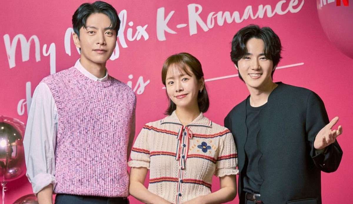 Main cast of the K-drama 'Behind Your Touch' posing together, featuring a man in a pink sweater vest, a woman in a striped dress, and another man in a black shirt, with a festive pink background and balloons.