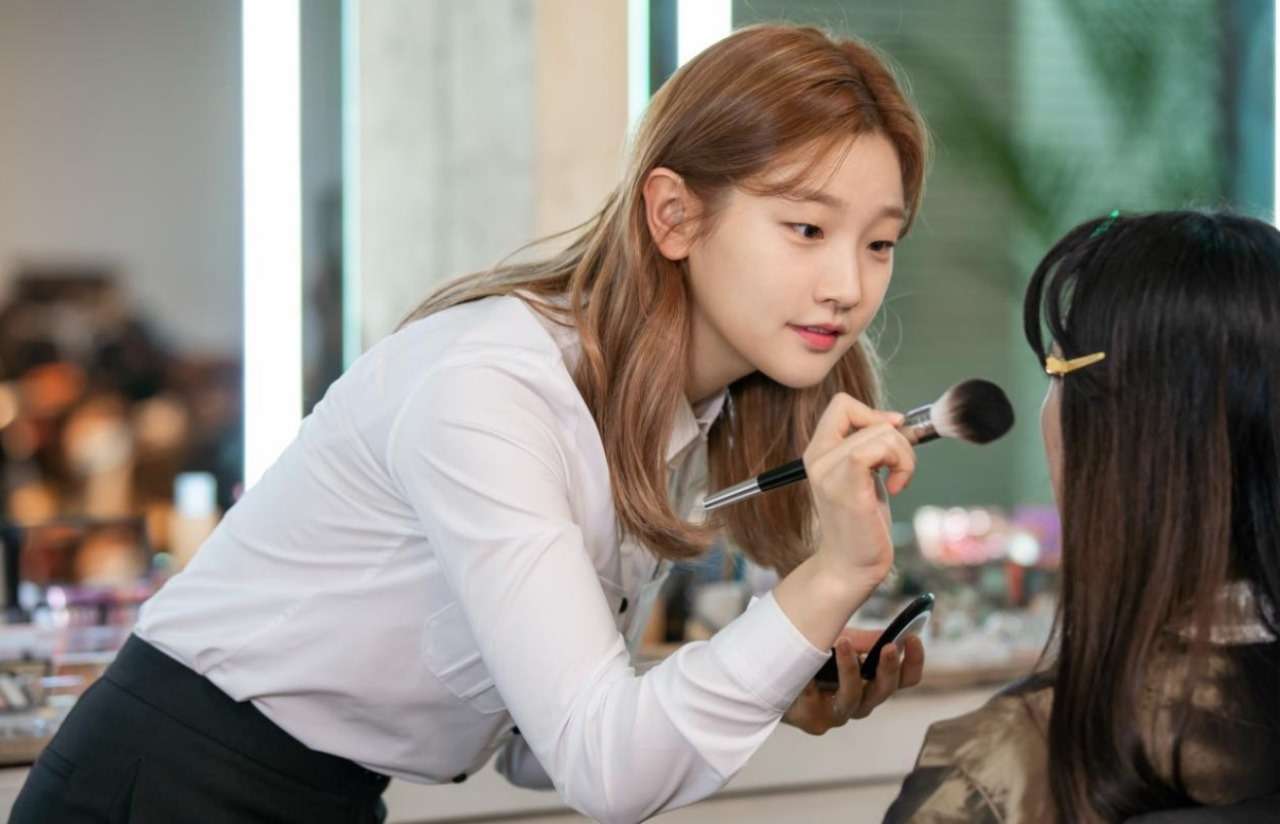 Ahn Jeong-ha (played by Park So-dam) applying makeup to a client in a scene from 'Record of Youth,' showcasing her skills as an aspiring makeup artist.