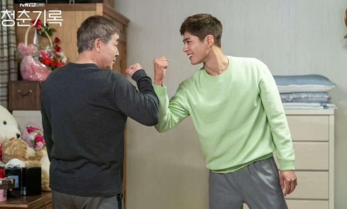 Sa Hye-jun (Park Bo-gum) sharing a playful fist bump with his father in a heartwarming scene from 'Record of Youth,' showcasing their close father-son relationship.