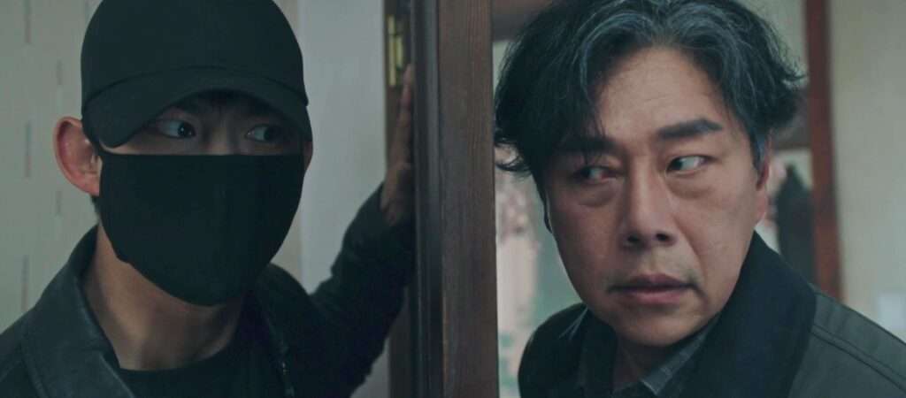 Tense scene featuring a masked figure in a cap confronting an older man in a suit, highlighting the suspenseful and dramatic narrative of the drama.