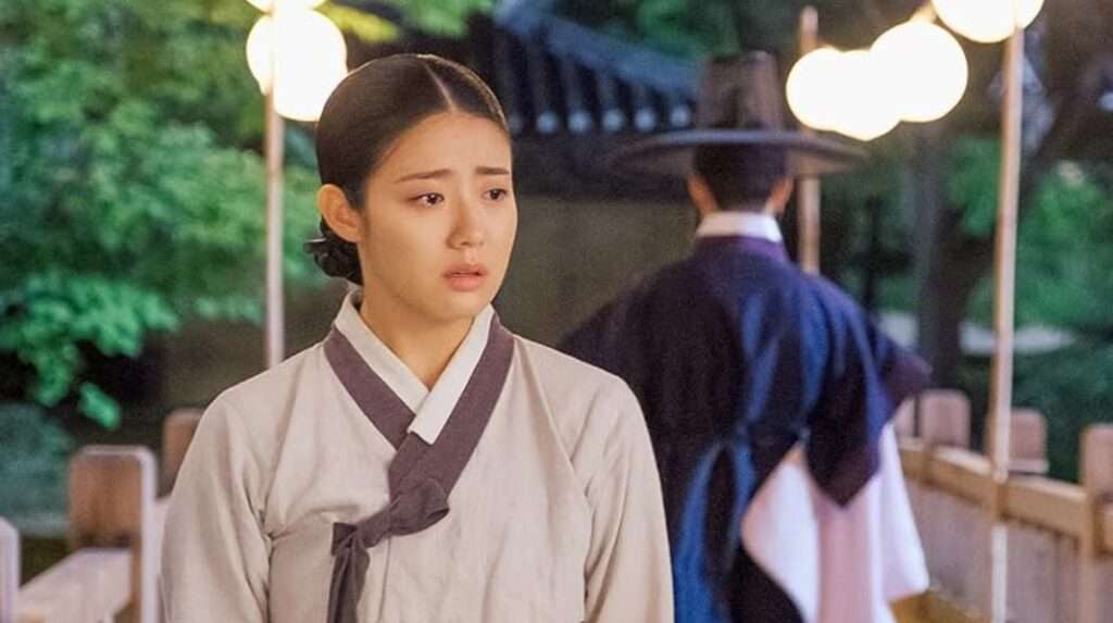 A woman dressed in traditional clothing poses next to a man in a suit, highlighting a blend of cultural and contemporary styles. 