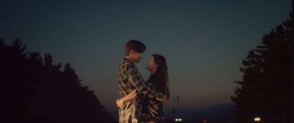 A romantic embrace between the leads of Love Struck in the City under a twilight sky with trees, capturing the K-drama's emotional depth.