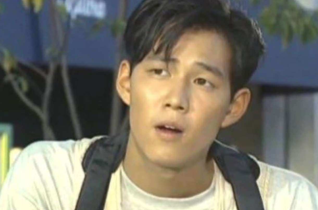 Young Lee Jung-jae in casual white shirt and backpack, captured in an expressive moment from his Lee Jung-jae profile and biography.
